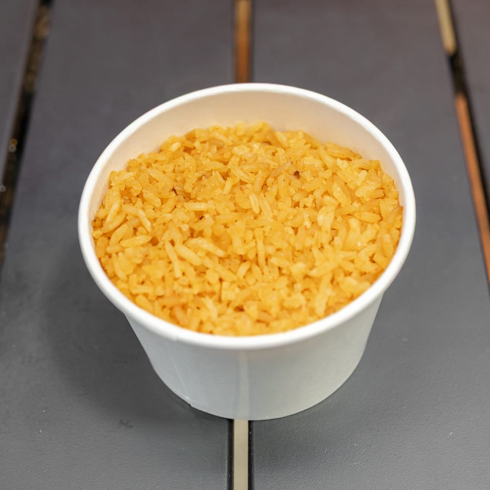 Bowl of seasoned golden rice on a dark tabletop.