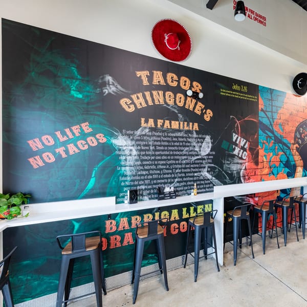 A vibrant mural at Tacos Ponchos features "No Life No Tacos" and "Tacos Chingones" with bar seating.
