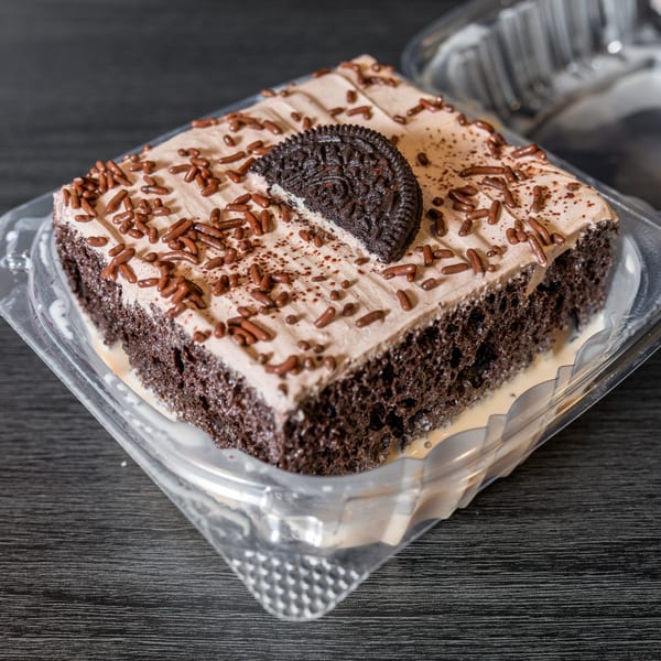 Chocolate cake with light brown frosting, chocolate sprinkles, and a half Oreo cookie on top.