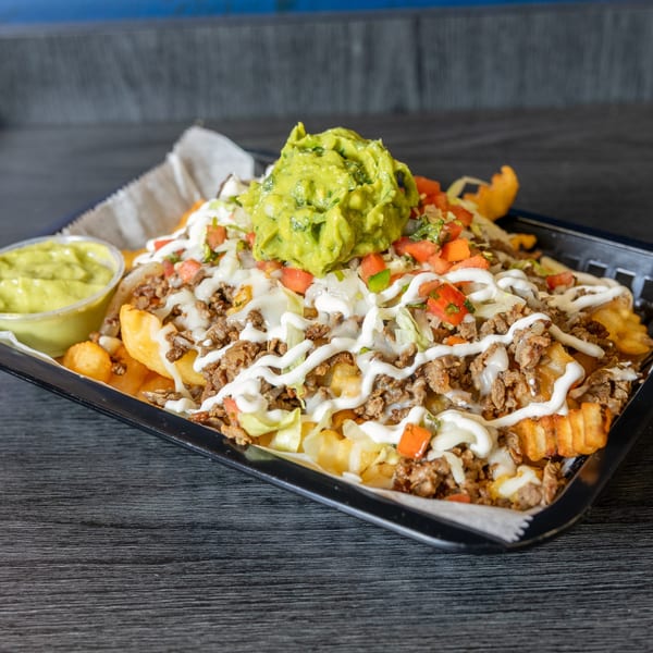 Tacos Ponchos' loaded carne asada fries with guacamole, sour cream, pico de gallo, and lettuce.