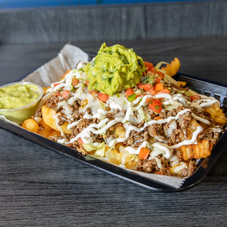 Tacos Ponchos' loaded carne asada fries with guacamole, sour cream, pico de gallo, and lettuce.