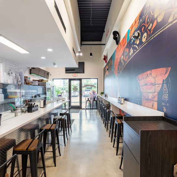Interior of Tacos Ponchos with a long counter, bar stools, and a colorful mural on the wall.
