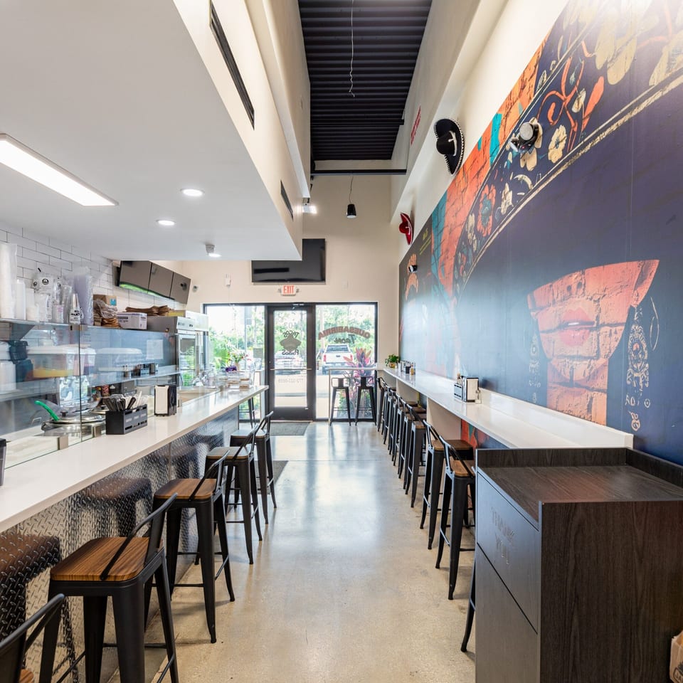 Interior of Tacos Ponchos with a long counter, bar stools, and a colorful mural on the wall.